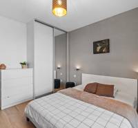 Ložnice v 2pokojovém bytě s podlahou s dřevěným dekorem a moderním nábytkem.