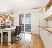 Kuchyně v 2pokojovém bytě s jídelním stolem a podlahou s dřevěným dekorem.