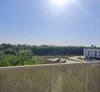 Výhled z balkonu v Bratislavě - Ružinov na Ivanské cestě s budovami a zelení.