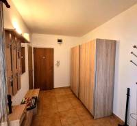 Předsíň v 2-pokojovém bytě s věšáky, skříní a podlahou s dřevěným dekorem.