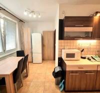 Kuchyně v 2-pokojovém bytě s jídelním stolem a spotřebiči.