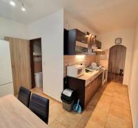 Kuchyně v 2pokojovém bytě s dlažbou, dřevěným dekorem a zařízením.