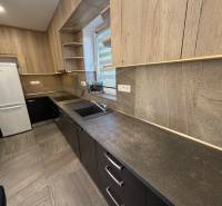 Kuchyně v rodinném domě s dřevěným dekorem a bílou lednicí.