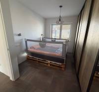 Ložnice v rodinném domě s postelí z palet a velkou skříní.