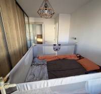 Pokoj s dětskou ohrádkou a vestavěnou skříní v rodinném domě, podlaha s dřevěným dekorem.