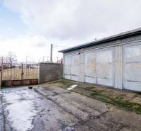 Brána a plechový sklad s betonovou plochou na Nádražní ulici v Šenkvicích.