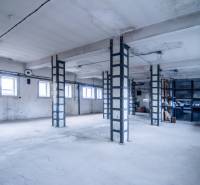 Prostory se sloupy a okny využívané jako sklady a haly.