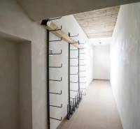 Úzký interiérový prostor ve skladu s kovovými věšáky na stěně.