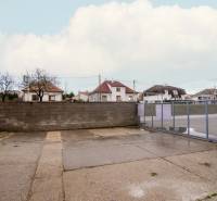 Exteriér na Nádražní ulici v Šenkvicích, vedle skladů a hal s ocelovou bránou.