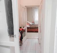 Úzká bílá chodba vede k dětskému pokoji s postelí v rodinném domě.