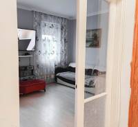 Obývací pokoj v rodinném domě s televizí a podlahou s dřevěným dekorem.