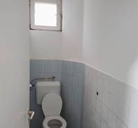 Koupelna v rodinném domě s modrými obklady a malým oknem.