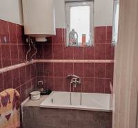 Koupelna v rodinném domě se sprchou, vanou, oknem a bojlerem.