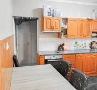 Kuchyně v rodinném domě s dřevěnými skříňkami a stropním obkladem.