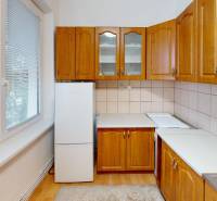 Kuchyně se světlými skříňkami a podlahou s dřevěným dekorem ve 4-pokojovém bytě.