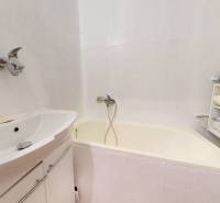 Koupelna s vanou a regálem ve 4-pokojovém bytě s uloženým prádlem.