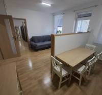 Interiér s pohovkou, jídelním stolem a podlahou s dřevěným dekorem v 2-pokojovém bytě.