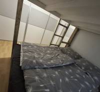 Ložnice v 2-pokojovém bytě s podlahou s dřevěným dekorem a palandou.