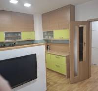 Kuchyně v 2pokojovém bytě s podlahou s dřevěným dekorem a barevnými skříňkami.