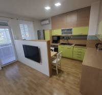 Kuchyně v 2-pokojovém bytě s podlahou s dřevěným dekorem a světlou linkou.