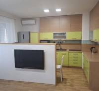 Kuchyně v 2-pokojovém bytě s podlahou s dřevěným dekorem a zelenými skříňkami.