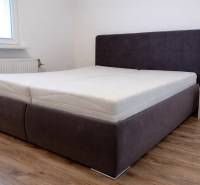 Ložnice s postelí a podlahou s dřevěným dekorem ve 3-pokojovém bytě.