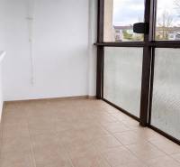 Zasklený balkon 3pokojového bytu, podlaha s dlažbou, výhled na okolí.