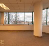 Interiér kanceláří s velkými okny a sloupem, podlaha s dřevěným dekorem.