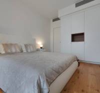 Ložnice s manželskou postelí, šatní skříní a podlahou s dřevěným dekorem v 2pokojovém bytě.