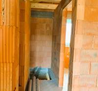 Interiér s cihlovými zdmi, dřevěným stropem a položenými trubkami v nové chatě.