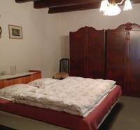 Ložnice v rodinném domě s postelí, vestavěnou skříní a venkovským dekorem.