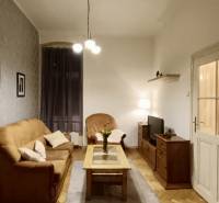 Obývací pokoj v 3-pokojovém bytě s podlahou s dřevěným dekorem, útulné posezení a osvětlení.