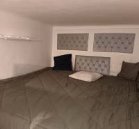 Ložnice v 3pokojovém bytě s nízkým stropem, pukovými panely na stěně a podlahou s dřevěným dekorem.