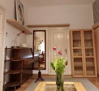 Interiér 3-pokojového bytu se stolem, vázou s květinami a dřevěným dekorem podlahy.