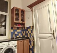Kuchyně ve 3-pokojovém bytě s barevnými obklady, dřevěnou linkou a pračkou.