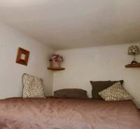 Ložnice ve 3-pokojovém bytě s dekorativními polštáři a noční lampou na poličce.