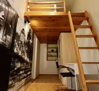 Pokoj v 3pokojovém bytě s palandou a stolem, podlaha s dřevěným dekorem.