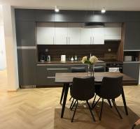 Kuchyně ve 3-pokojovém bytě se šedými skříňkami a podlahou s dřevěným dekorem.