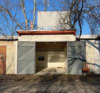 Garáž na Agátové ulici v Bratislavě - Dúbravce s plechovými dveřmi a židlí venku.