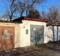 Různobarevné garáže na Agátové ulici v Bratislavě - Dúbravce obklopené stromy.