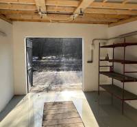 Garáže na Agátové ulici v Bratislavě-Dúbravce se železnými policemi a otevřenými dveřmi.