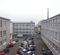 Budovy kanceláří na Masarykově ulici v Prešově s množstvím zaparkovaných aut na dvoře.