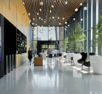 Recepce v kanceláři se skleněnými stěnami, rostlinami a pohodlným sezením.