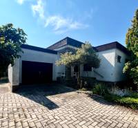 Rodinný dům v Ivance pri Dunaji s garáží a květinovým záhonem, na dlážděném chodníku.