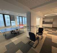 Kanceláře se stolním tenisem, posezením a kuchyňkou na podlaze s dřevěným dekorem.