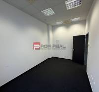 Kanceláře s bílými stěnami a tmavým kobercem.