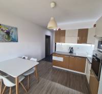 Kuchyně v 2pokojovém bytě s podlahou s dřevěným dekorem a jídelním stolem.