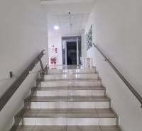 Schodiště s bílými stěnami a dlaždicovou podlahou vede do vstupu v 2-pokojovém bytě.