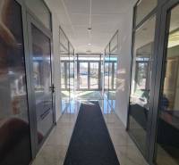 Světlá chodba se skleněnými dveřmi a mramorovou podlahou v Komárně, vhodná pro 2-pokojový byt.