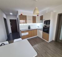 Kuchyně se spotřebiči a stolem, podlaha s dřevěným dekorem v 2pokojovém bytě.